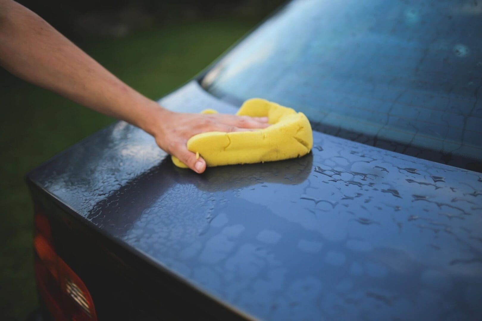 A person cleaning the hood of their car.